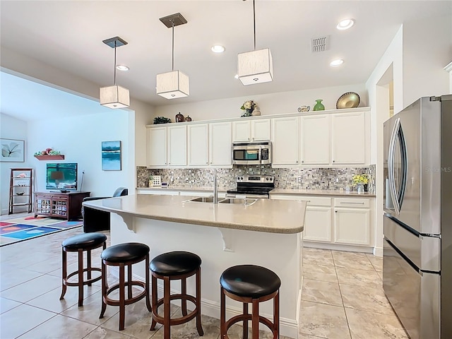 kitchen with a kitchen bar, light countertops, decorative backsplash, stainless steel appliances, and a sink