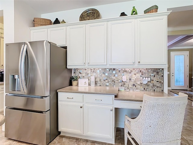 kitchen featuring stainless steel refrigerator with ice dispenser, backsplash, white cabinetry, light countertops, and built in study area