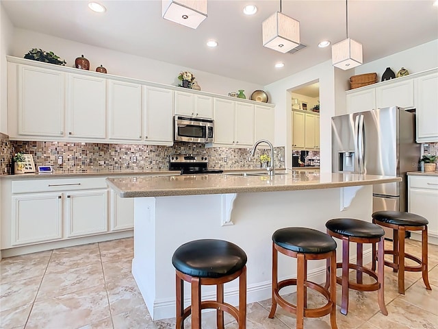kitchen featuring a sink, stainless steel appliances, a breakfast bar, and decorative backsplash