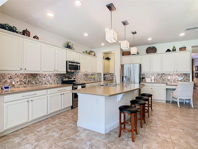 kitchen with a sink, a breakfast bar area, white cabinetry, and stainless steel appliances