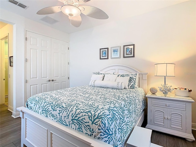 bedroom with dark wood-style flooring, visible vents, a closet, and ceiling fan