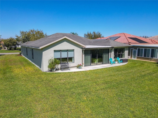 back of property with stucco siding, a lawn, and a patio area