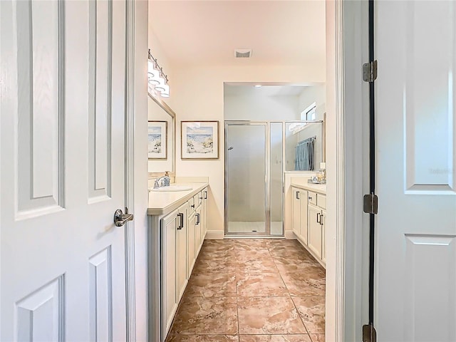 full bath featuring a shower stall, two vanities, visible vents, and a sink
