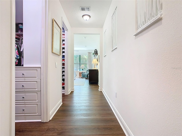 hallway with dark wood-style floors, visible vents, and baseboards