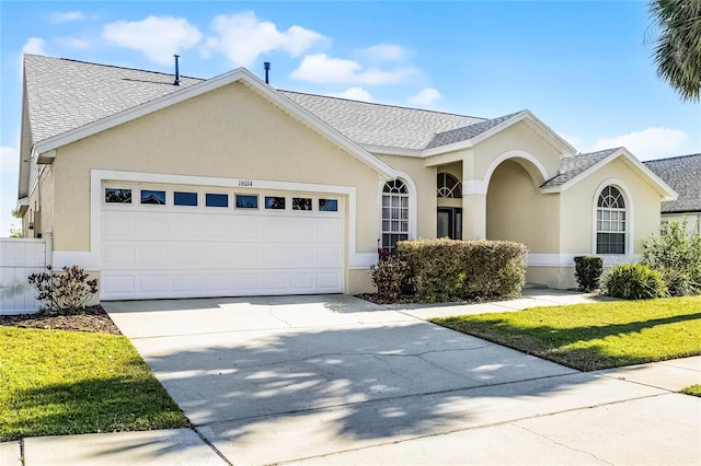 ranch-style house featuring concrete driveway, roof with shingles, a front yard, stucco siding, and an attached garage