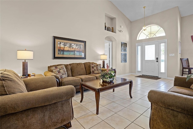 living room with light tile patterned floors, arched walkways, baseboards, and high vaulted ceiling