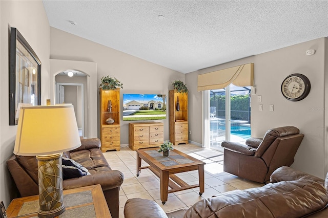 living area featuring lofted ceiling, light tile patterned flooring, arched walkways, and a textured ceiling