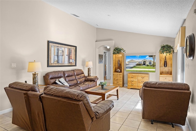 living area with visible vents, a textured ceiling, light tile patterned floors, baseboards, and vaulted ceiling