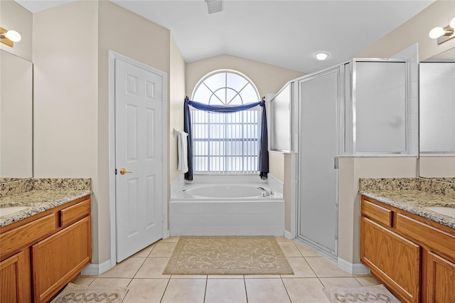 bathroom with a garden tub, two vanities, a stall shower, vaulted ceiling, and tile patterned floors