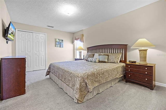 bedroom featuring a closet, visible vents, carpet flooring, and a textured ceiling