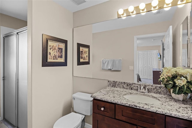 bathroom with vanity, a shower stall, toilet, and visible vents