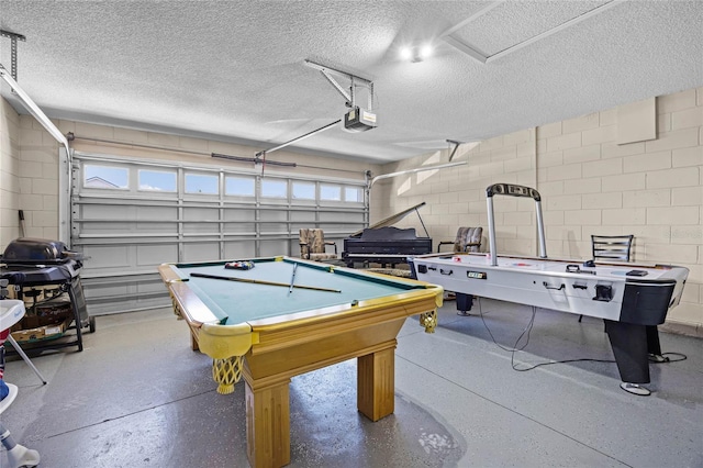 rec room with a garage, a textured ceiling, speckled floor, and concrete block wall