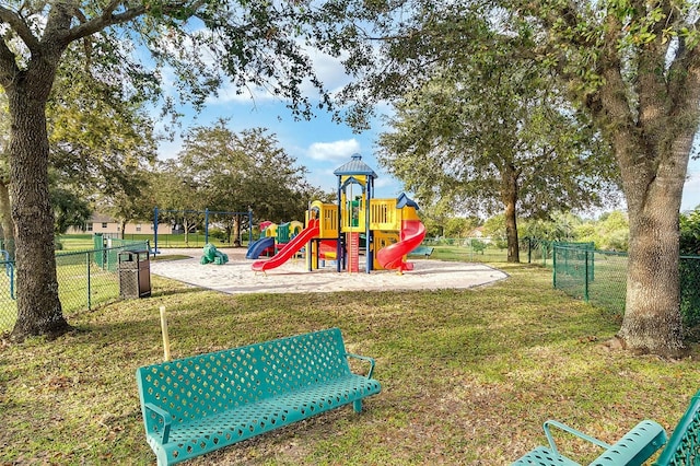 community jungle gym featuring a yard and fence