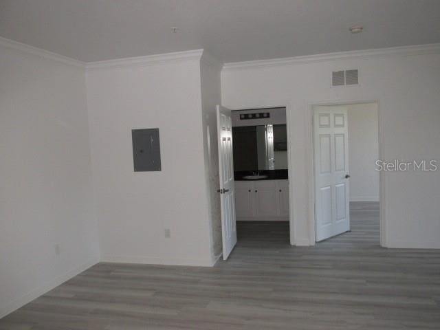 unfurnished room featuring electric panel, visible vents, crown molding, and wood finished floors