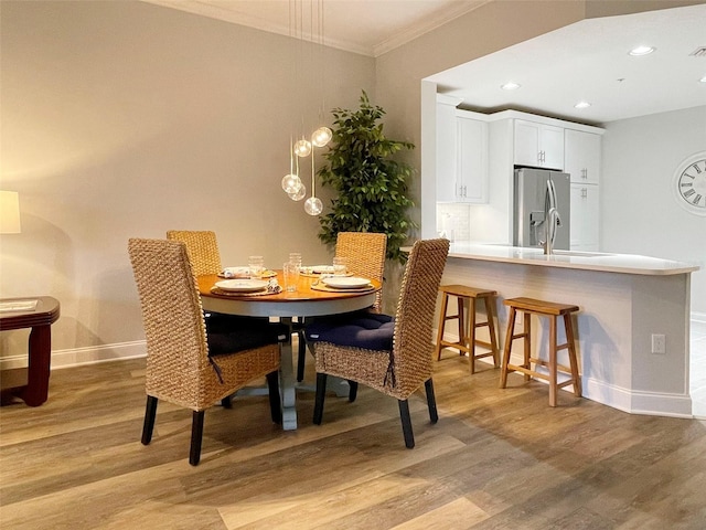 dining space featuring recessed lighting, light wood-type flooring, baseboards, and ornamental molding