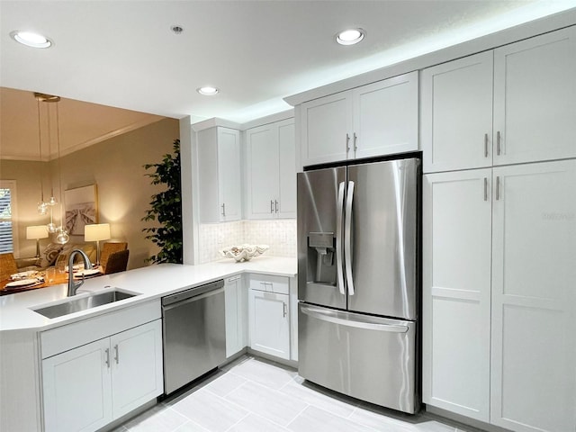 kitchen featuring a sink, appliances with stainless steel finishes, a peninsula, and light countertops