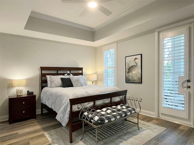 bedroom with a ceiling fan, a raised ceiling, wood finished floors, and baseboards