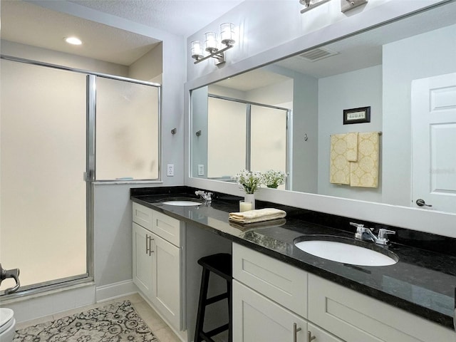 bathroom with a sink, a stall shower, double vanity, and tile patterned floors