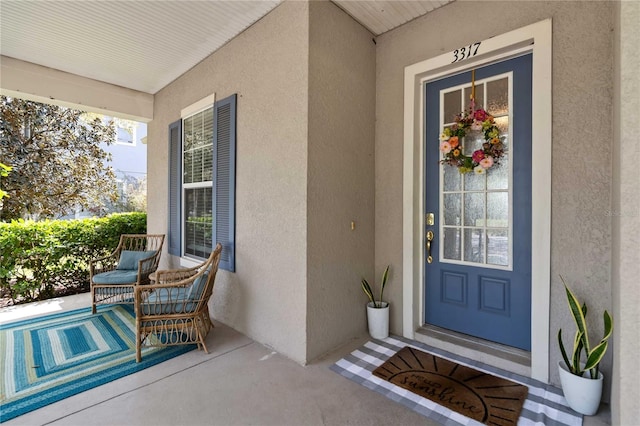 property entrance with stucco siding and covered porch