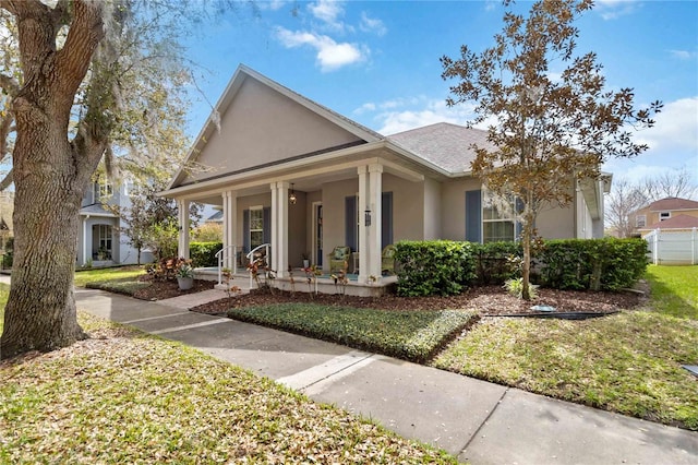 view of front of home featuring covered porch, stucco siding, and a front lawn