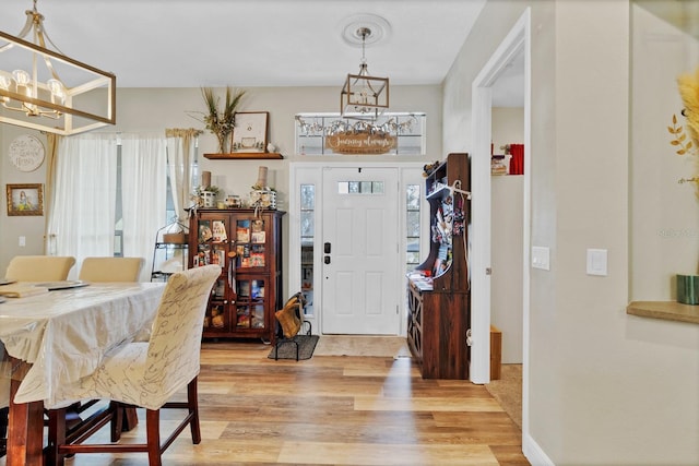 foyer featuring a wealth of natural light, light wood-type flooring, and an inviting chandelier