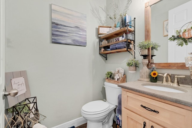 half bathroom with vanity, toilet, and baseboards