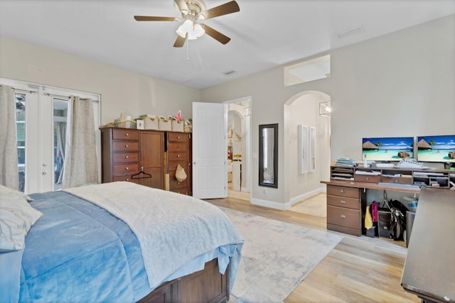 bedroom featuring wood finished floors, french doors, arched walkways, baseboards, and ceiling fan