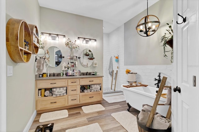 bathroom featuring double vanity, a sink, a freestanding bath, and wood finished floors