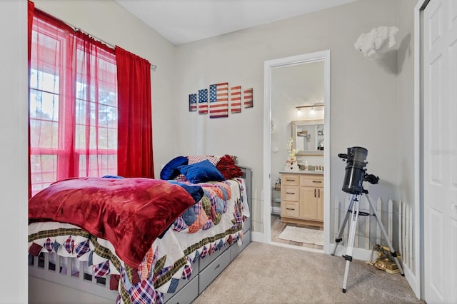 carpeted bedroom with connected bathroom and baseboards