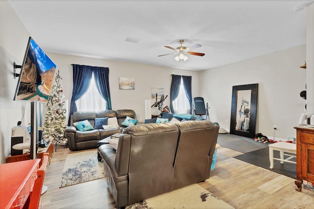 living room featuring baseboards, light wood finished floors, and ceiling fan