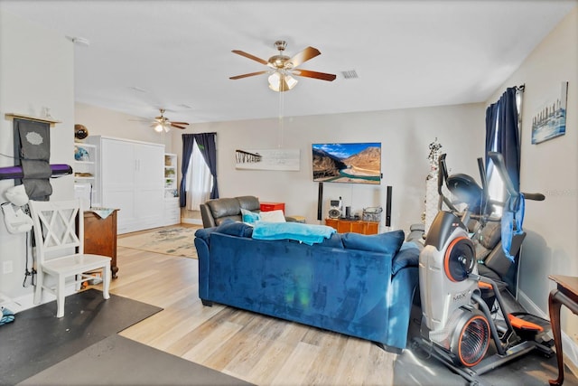 living room with ceiling fan, visible vents, and wood finished floors