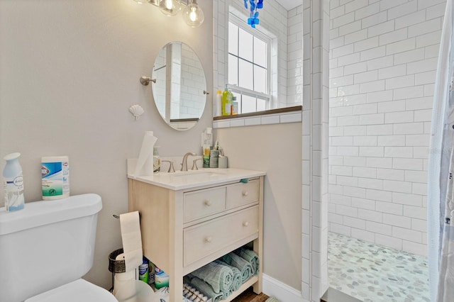 full bathroom with a tile shower, toilet, and vanity