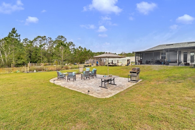 view of yard featuring a patio area, fence, a sunroom, and a fire pit