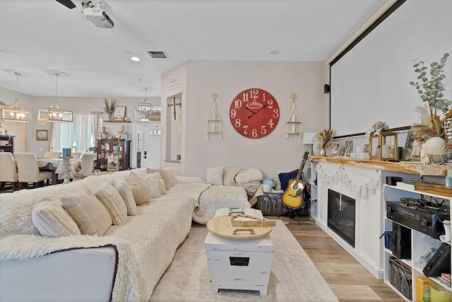 living area with visible vents, a notable chandelier, recessed lighting, light wood-style floors, and a fireplace