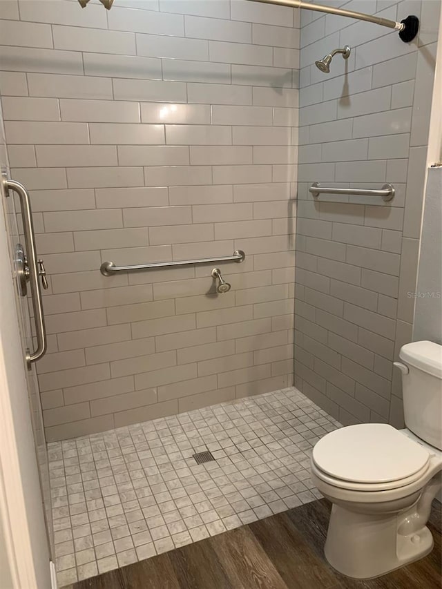 bathroom featuring a stall shower, toilet, and wood finished floors