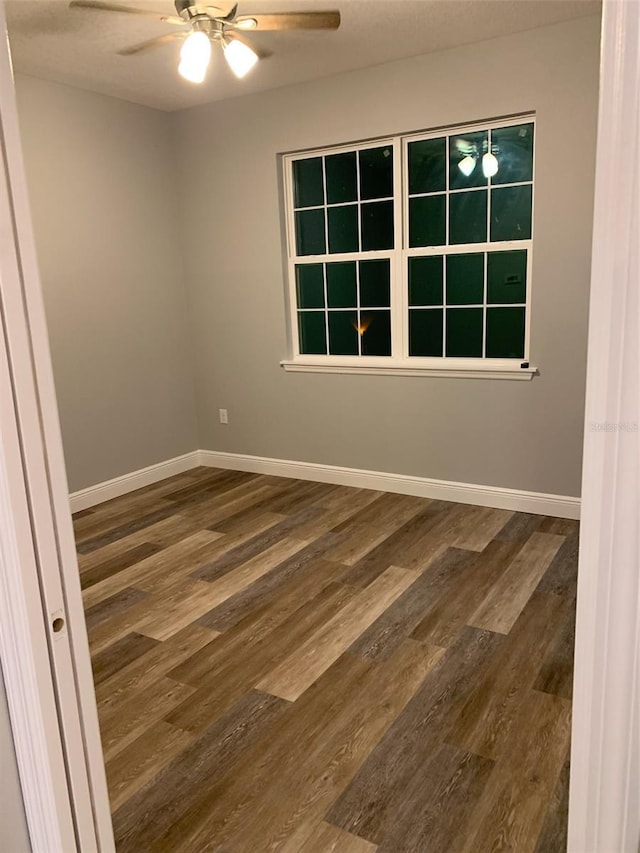 empty room with a ceiling fan, wood finished floors, and baseboards