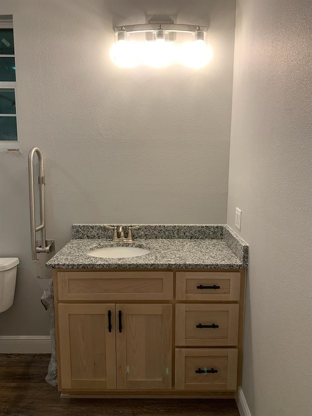 bathroom featuring toilet, vanity, baseboards, and wood finished floors