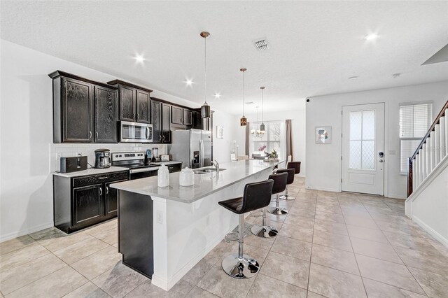 kitchen featuring visible vents, a sink, appliances with stainless steel finishes, a breakfast bar area, and light countertops