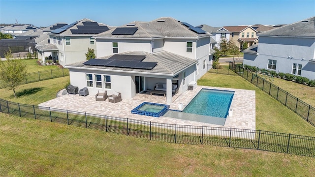 rear view of property featuring a yard, a fenced backyard, a pool with connected hot tub, a patio area, and a residential view