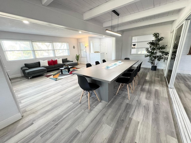 dining space with beamed ceiling, baseboards, and wood finished floors