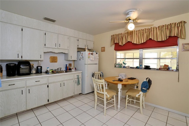 kitchen featuring light tile patterned flooring, freestanding refrigerator, ceiling fan, a sink, and light countertops