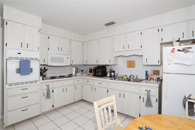 kitchen with visible vents, a sink, white appliances, light countertops, and light tile patterned floors