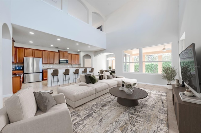 living room with recessed lighting, arched walkways, a high ceiling, and light tile patterned flooring