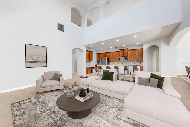 living room featuring light tile patterned floors, visible vents, and arched walkways