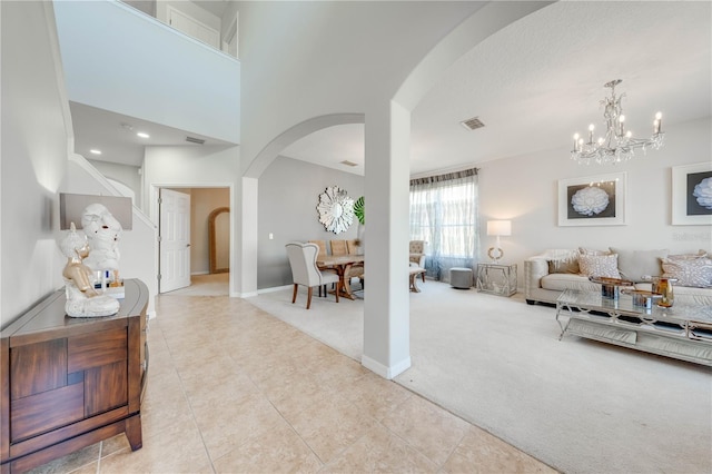 tiled living room featuring visible vents, baseboards, a high ceiling, arched walkways, and carpet flooring