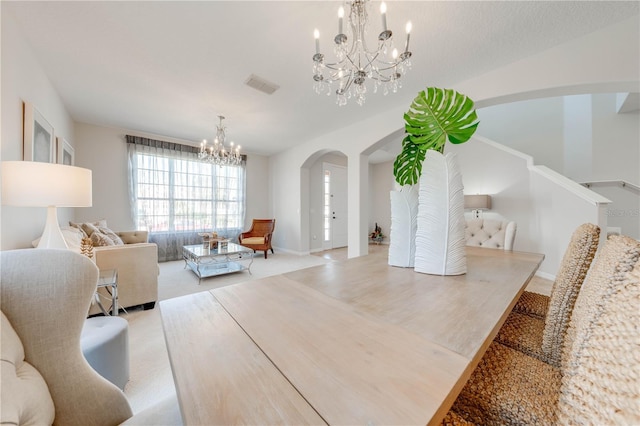 dining room featuring visible vents, arched walkways, a notable chandelier, and light colored carpet