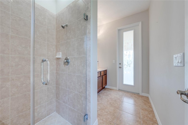 full bath featuring tile patterned floors, a stall shower, vanity, and baseboards