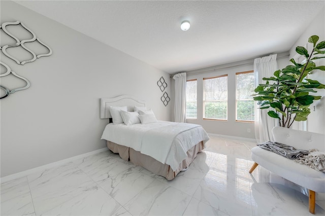 bedroom featuring marble finish floor, a textured ceiling, and baseboards