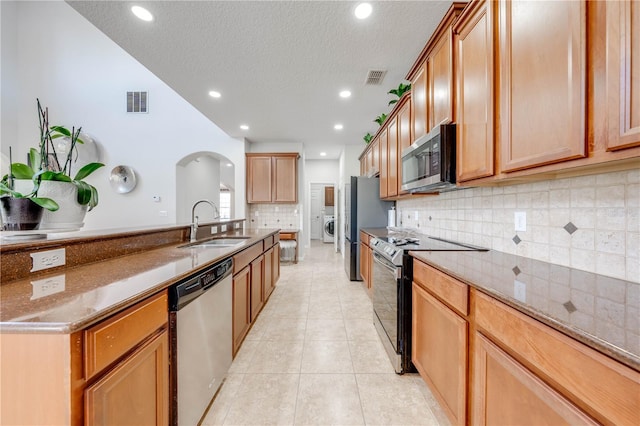 kitchen with visible vents, washer / dryer, light tile patterned flooring, stainless steel appliances, and a sink