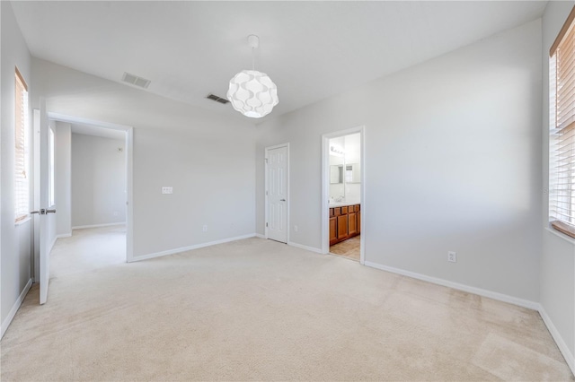 empty room featuring light carpet, visible vents, and baseboards